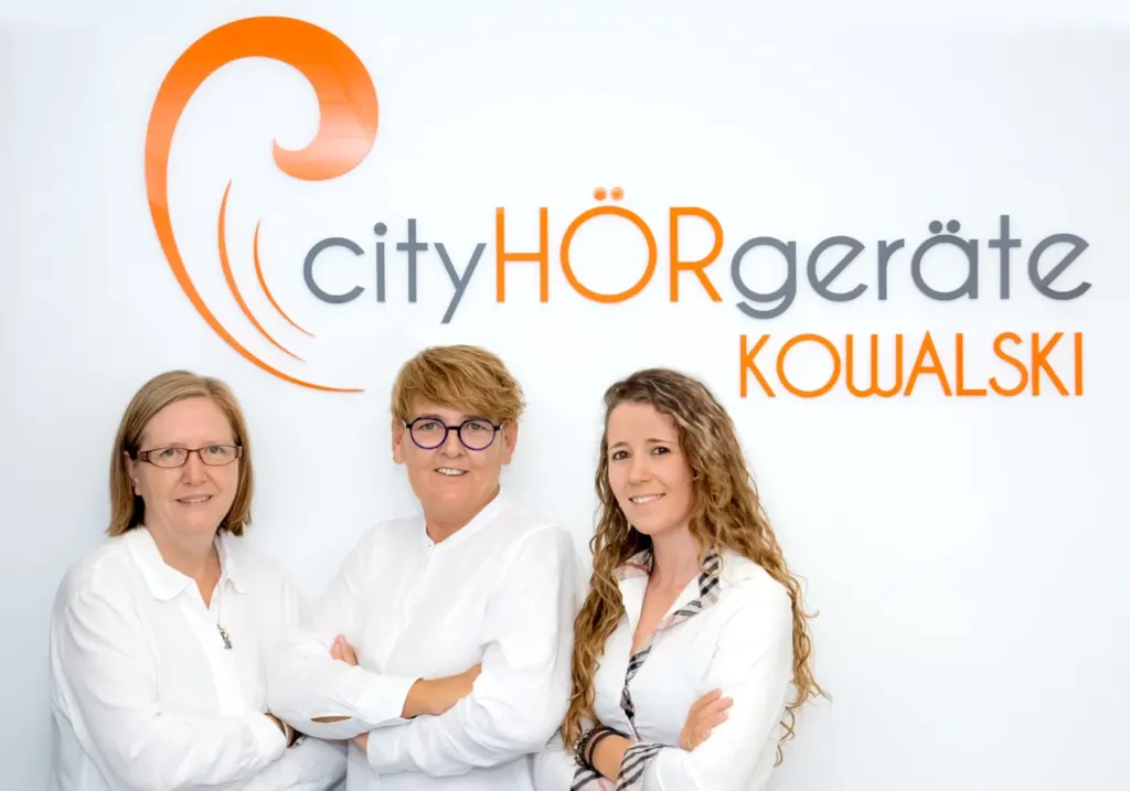 Das Team von CityHÖRgeräte Kowalski vor dem Firmenlogo