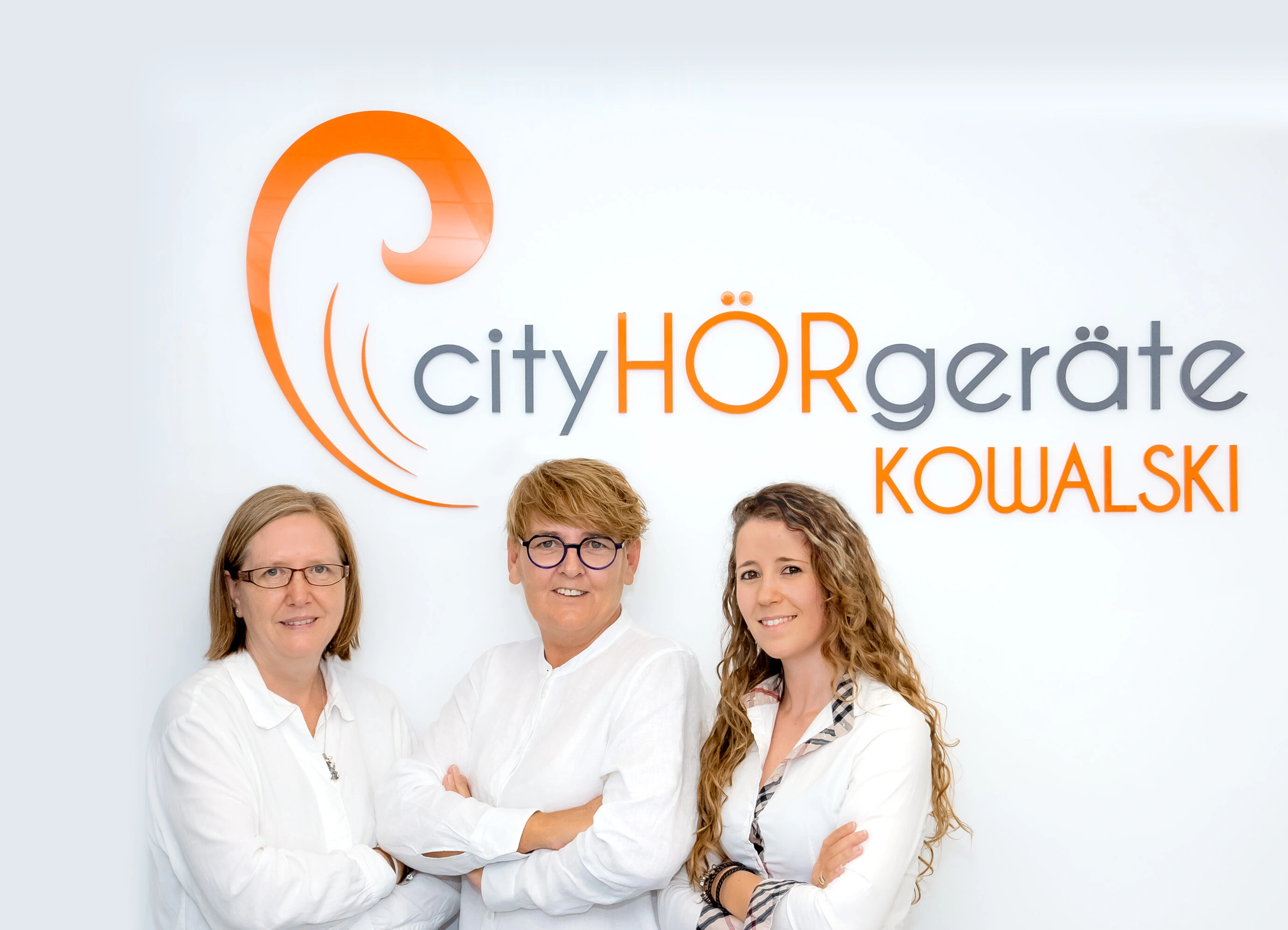 Das Team von CityHÖRgeräte Kowalski vor dem Firmenlogo
